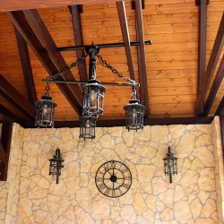 Kované nástenné a závesné svietidlá v letnom altánku pri penzióne